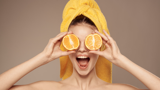 Self-Care: Image of a woman smiling while holding oranges on her eyes.